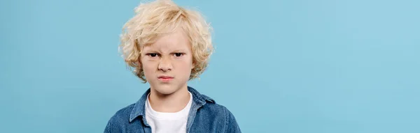 Panoramic shot of irritated and cute kid looking at camera isolated on blue — Stock Photo