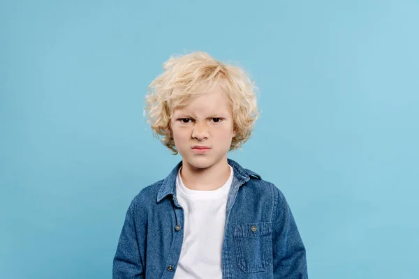 Irritiertes und süßes Kind, das isoliert auf blauem Grund in die Kamera blickt — Stockfoto