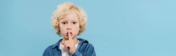 Plan panoramique de mignon enfant montrant geste secret et en regardant la caméra isolée sur bleu — Photo de stock