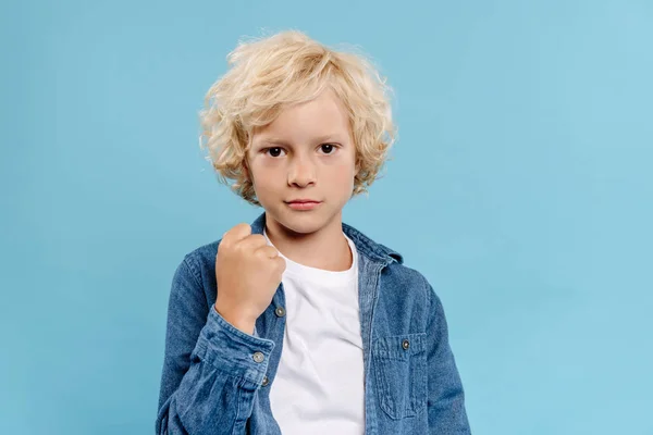 Mignon enfant regardant caméra et montrant poing isolé sur bleu — Photo de stock