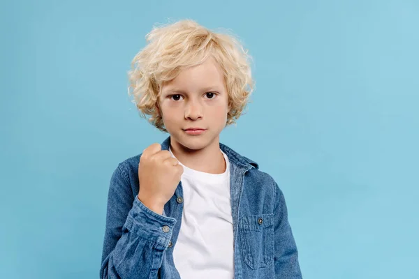 Cute kid looking at camera and showing fist isolated on blue — Stock Photo