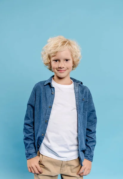 Smiling and cute kid looking at camera isolated on blue — Stock Photo