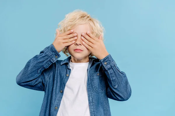 Kid in denim shirt obscuring face isolated on blue — Stock Photo