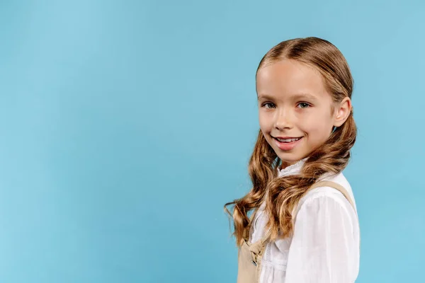 Smiling and cute kid looking at camera isolated on blue — Stock Photo