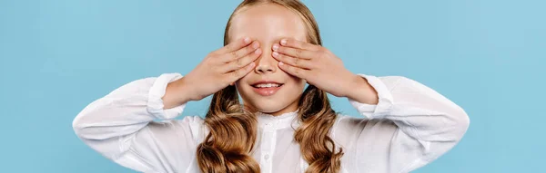 Plan panoramique d'un enfant souriant obscurcissant le visage isolé sur bleu — Photo de stock