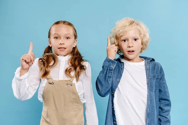 Shocked and cute kids looking at camera and showing idea sign isolated on blue — Stock Photo