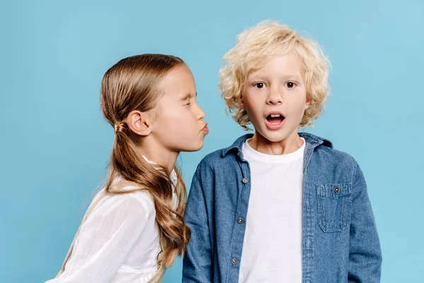 Kid with closed eyes kissing shocked friend isolated on blue — Stock Photo