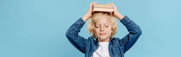 Tiro panorâmico de criança bonito com olhos fechados segurando livros isolados em azul — Fotografia de Stock