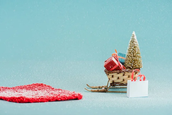 Red carpet and wicker sled with christmas tree and gift boxes on blue background — Stock Photo