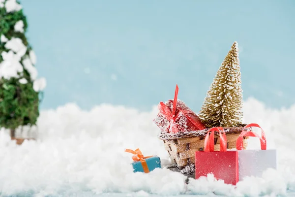 Coffrets cadeaux et sapin de Noël en luge d'osier, sacs à provisions dans la neige — Photo de stock