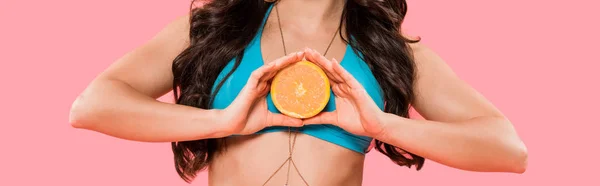 Panoramic shot of girl in swimsuit holding half of orange isolated on pink — Stock Photo