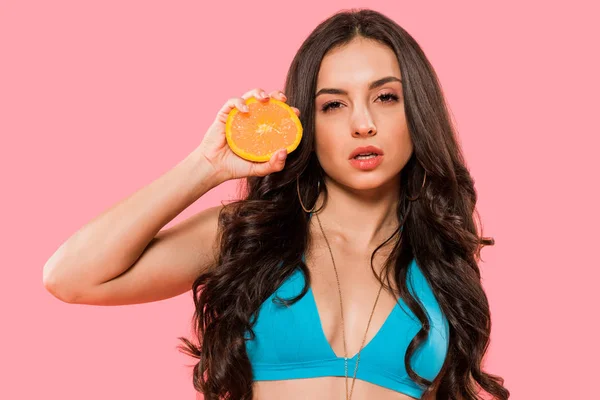 Sexy mujer sosteniendo la mitad de naranja aislado en rosa - foto de stock