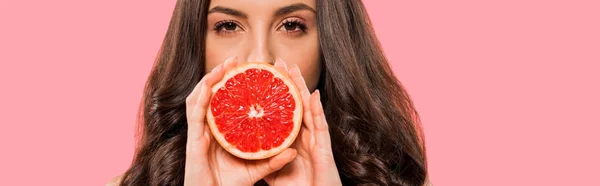 Panoramic shot of woman in swimsuit covering face with half of grapefruit isolated on pink — Stock Photo