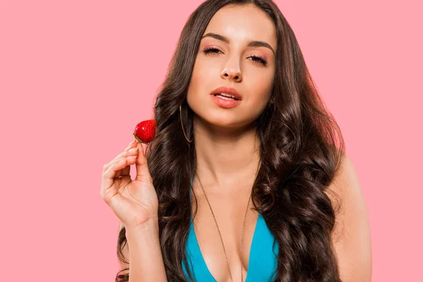 Atractiva mujer sosteniendo fresa aislado en rosa - foto de stock