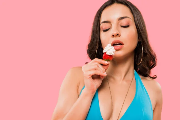 Young and sexy woman holding strawberry with whipped cream isolated on pink — Stock Photo