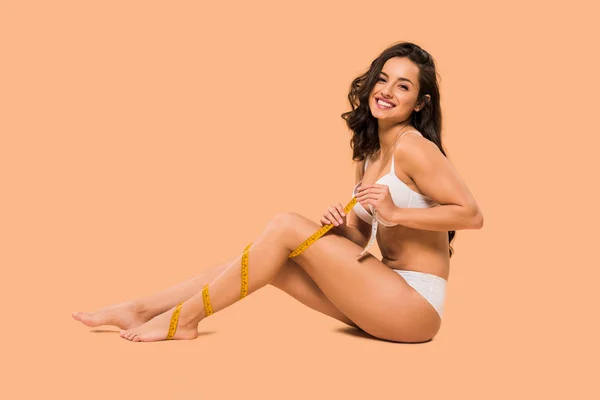 Cheerful woman in underwear smiling and sitting on beige — Stock Photo