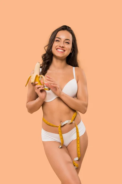 Cheerful woman in underwear holding peeled banana isolated on beige — Stock Photo