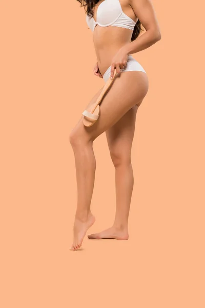 Vista recortada de la joven mujer sosteniendo cepillo de cuerpo aislado en beige — Stock Photo