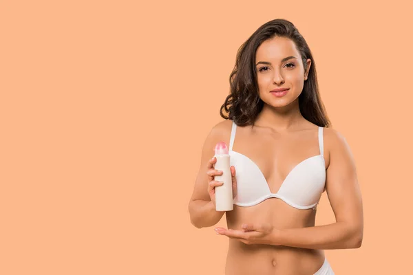 Attraktive Frau hält Deo-Spray isoliert auf beige — Stockfoto