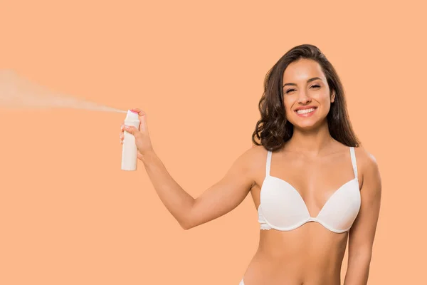 Mujer alegre sosteniendo spray desodorante aislado en beige - foto de stock