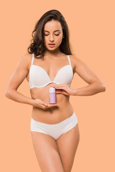 Mulher atraente segurando rolo desodorizante em isolado no bege — Fotografia de Stock