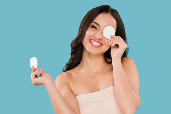 Mujer feliz cubriendo el ojo con almohadilla de algodón aislado en azul - foto de stock