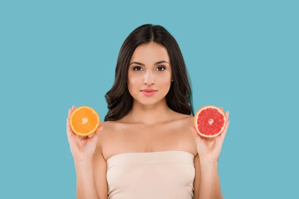 Mulher atraente segurando metades de laranja e toranja isolado em azul — Fotografia de Stock