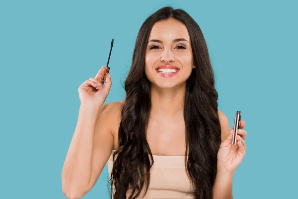 Happy woman holding mascara and smiling isolated on blue — Stock Photo
