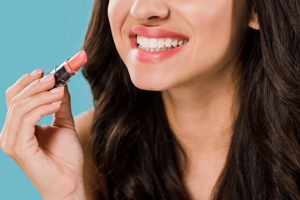 Recortado vista de alegre chica sosteniendo lápiz labial aislado en azul - foto de stock