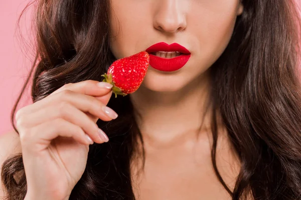 Vista cortada de mulher com lábios vermelhos segurando morango isolado em rosa — Fotografia de Stock