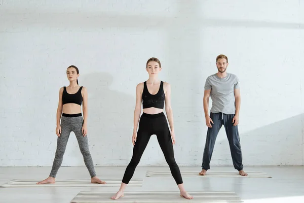 Hombres y mujeres jóvenes practicando yoga en pose estelar - foto de stock