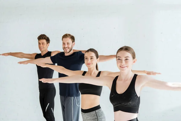 Smiling young people in sportswear practicing yoga in mountain open arm pose — Stock Photo