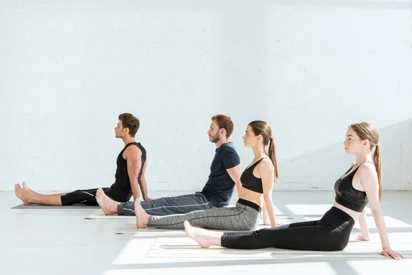 Jóvenes en ropa deportiva practicando yoga en pose de personal - foto de stock