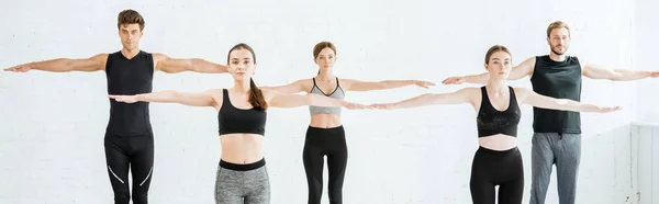 Panoramic shot of five young people practicing yoga in mountain open arm pose — Stock Photo