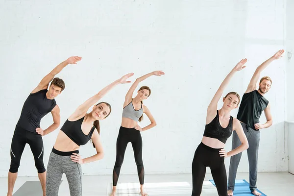 Five young people doing side tilt in star pose with hand on hip — Stock Photo