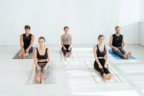 Five young people practicing yoga in staff pose — Stock Photo