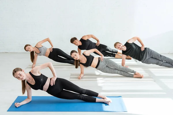 Cinque giovani che praticano yoga in posa tavola laterale — Foto stock