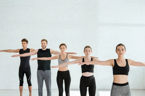Five young men and women practicing yoga in mountain open arm pose — Stock Photo
