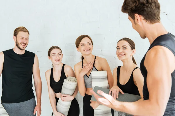 Cheerful friends talking while holding yoga mats — Stock Photo
