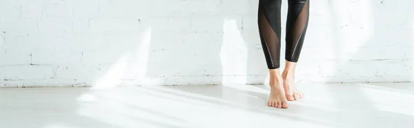 Cropped view of barefoot woman standing near white wall, panoramic shot — Stock Photo
