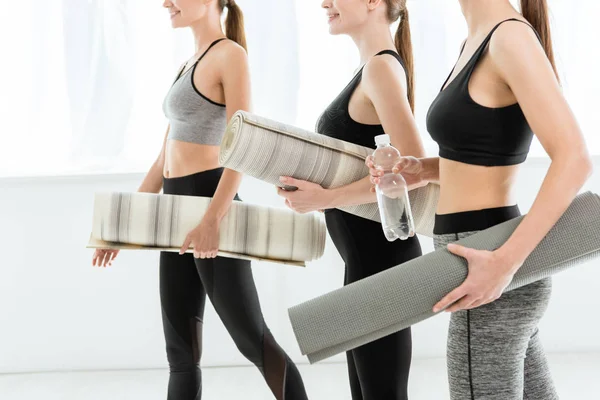 Cropped view of three young women holding yoga mats — Stock Photo