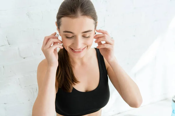 Young cheerful sportswoman listening music in earphones — Stock Photo