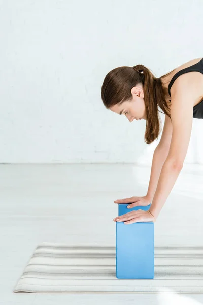 Junge Frau praktiziert Yoga, während sie sich mit den Händen auf Ständer stützt — Stockfoto