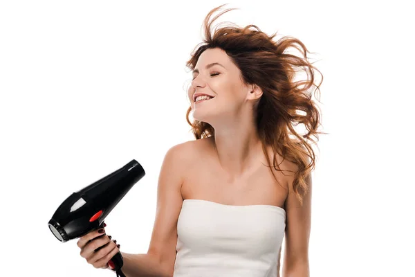 Feliz chica rizada usando secador de pelo aislado en blanco - foto de stock
