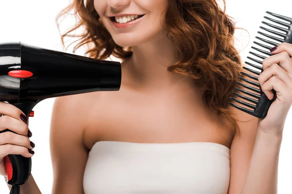 Обрезанный вид счастливой девушки с помощью фена, расчесывая волосы изолированы на белом — стоковое фото