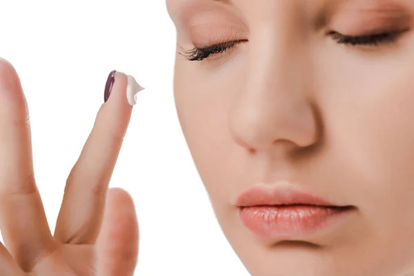 Primer plano de la mujer con los ojos cerrados y crema facial en el dedo aislado en blanco - foto de stock