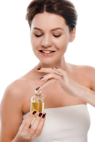 Cheerful woman looking at bottle with oil isolated on white — Stock Photo