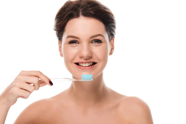 Mujer desnuda feliz sonriendo mientras sostiene el cepillo de dientes aislado en blanco - foto de stock