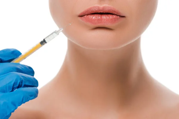 Vista recortada do cirurgião plástico em seringa luva de látex azul segurando perto de paciente nu isolado em branco — Fotografia de Stock
