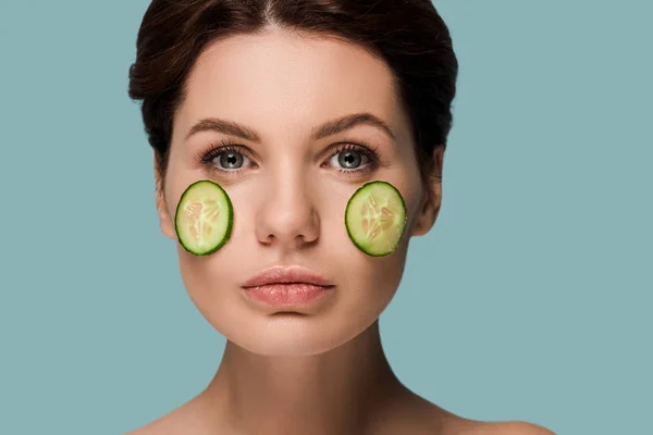 Attractive woman with cucumbers on face isolated on blue — Stock Photo